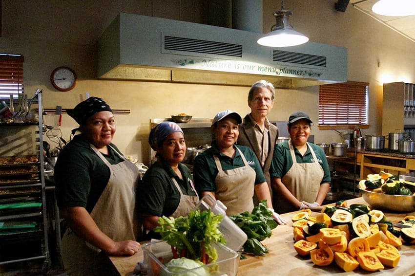Kitchen staff at Casa de Luz behind a counter of freshly prepared vegetables
